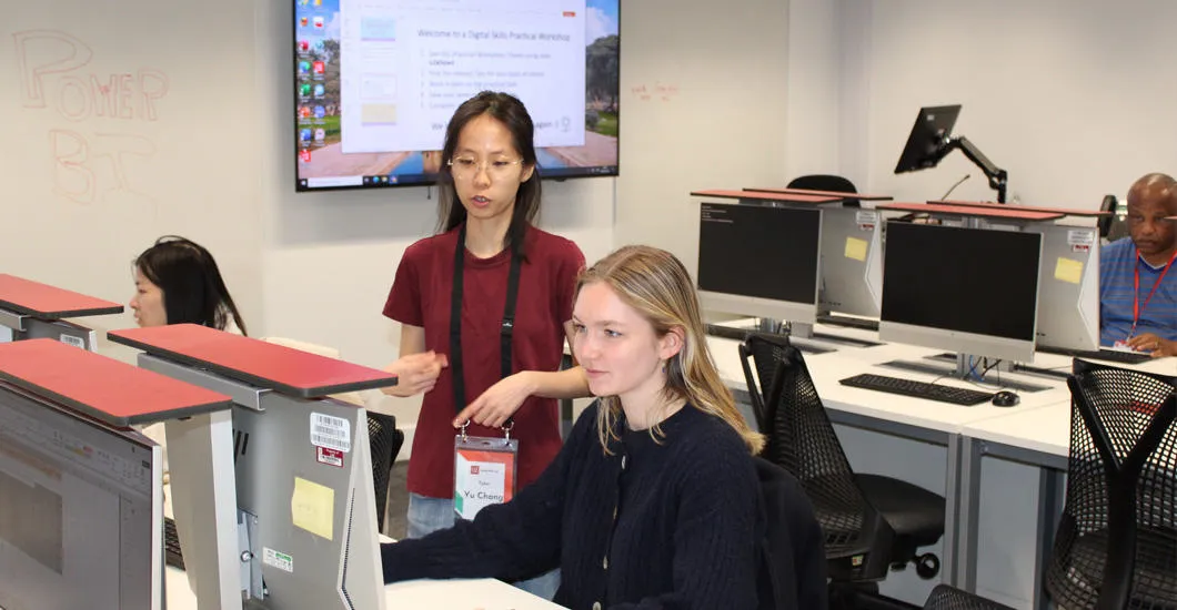 A Digital Skills Lab instructor gives guidance to a student working on a computer